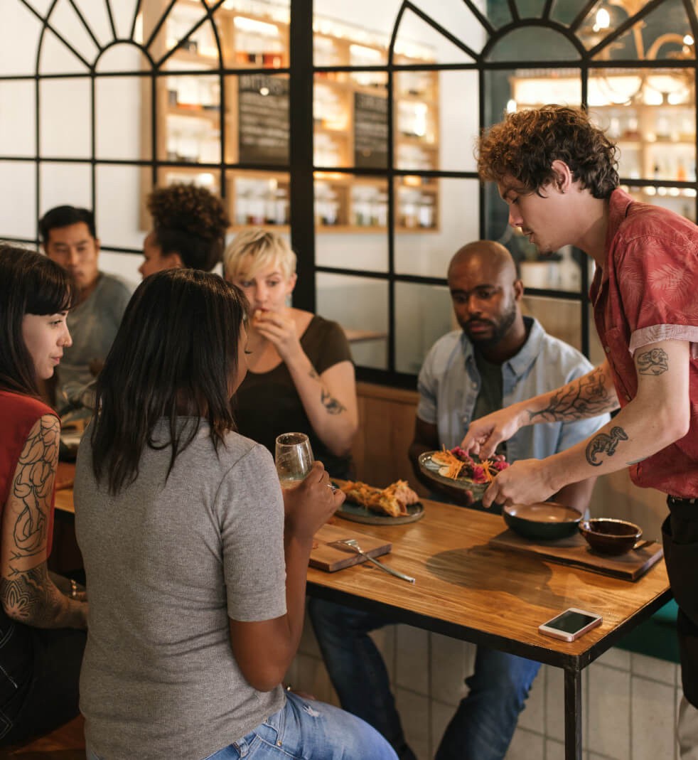634x648-hero-case-study-groupon A person serving a plate of tacos to a table of people.